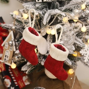 Red and white knitted mini Christmas stockings hanging on a snow-covered Christmas tree