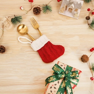 Christmas knit stocking cutlery holder with golden fork and spoon on festive wood