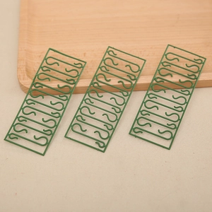 Green S-shaped plastic hooks set for Christmas decorations on a wooden tray