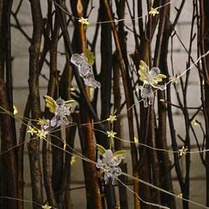 Transparent angel ornaments with gold wings and LED fairy lights on tree branches