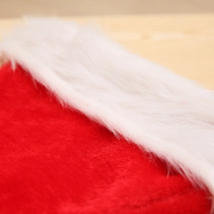 Classic red plush Christmas hat with thick white faux fur trim on wooden background