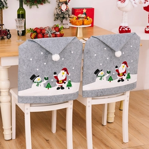 Detail of gray Christmas chair covers with snowman and Santa patterns for holiday dining decor