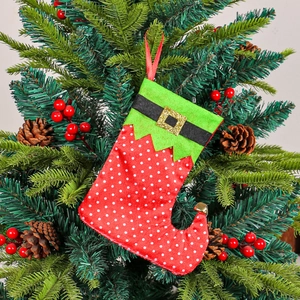 Elf style Christmas stocking hanging ornament with red polka dots and belt on a tree