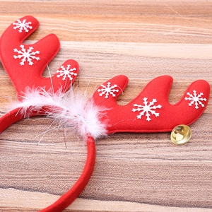 Christmas reindeer antler headband with white feathers and gold bell on wooden background