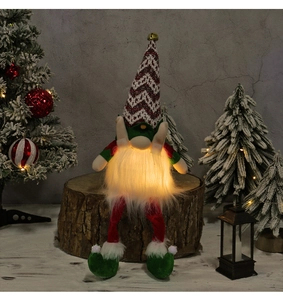 Detail of a glowing Christmas gnome with warm LED light and striped knit hat on wood
