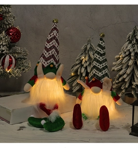 Detailed view of two Christmas gnomes with warm LED glowing long white beards and bells