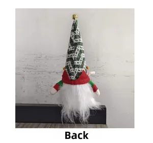 Rear view of a Christmas gnome with green wavy knit hat and a golden bell ornament