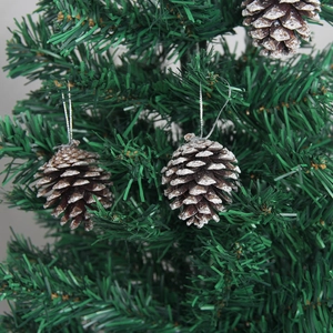 Set of three natural pine cones with white snow effect hanging on a green Christmas tree