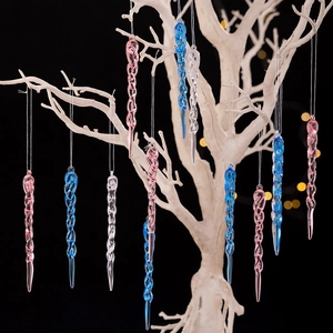Pink and blue spiral icicle Christmas tree ornaments on a winter branch with bokeh lights