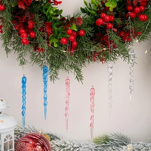 Pink and blue acrylic icicle Christmas ornaments with spiral texture on snowy pine branches