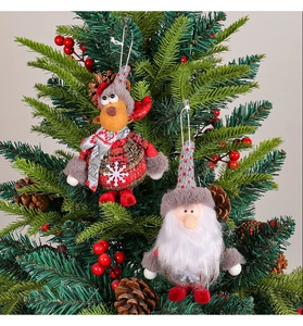 Detail of Christmas reindeer and gnome plush ornaments hanging on a festive pine tree branch