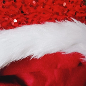 Macro shot of red reversible sequins and white faux fur trim on a plush Christmas hat