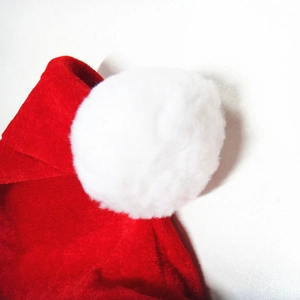 Detailed macro view of the fluffy white pom-pom and soft red velvet Christmas hat fabric