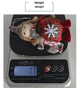 Close-up of a 17g Christmas doll pendant in plaid dress on a kitchen scale for weight display