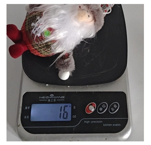 Lightweight 16g plush Christmas gnome ornament weighing on a digital scale for size