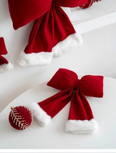 Detail view of red velvet Christmas bows with white faux fur trim and gold sequin ornaments