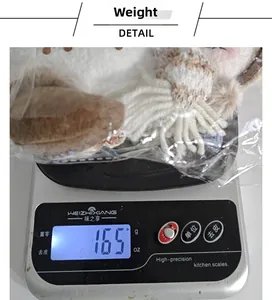 Détail d'une poupée bonhomme de neige en tricot blanc pesant 165g sur une balance
