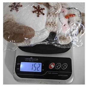 Détail montrant une poupée bonhomme de neige en peluche pesant 152 grammes sur la balance