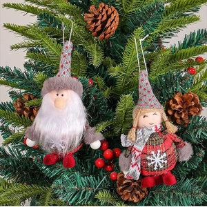 Christmas gnome and plush doll hanging ornaments on pine tree with berries and cones