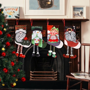 Set of 4 Christmas stockings with long elf legs hanging on a rustic wooden fireplace