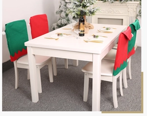 Detail of red and green elf hat chair covers with white pom-poms for Christmas dining decor
