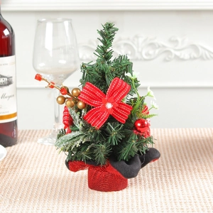 Mini Christmas tree table decoration with red bows and berries on a holiday dinner table