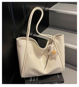 Detail of creamy white quilted tote bag featuring a horse charm and wrinkled texture