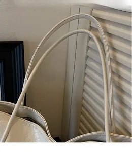 Detail of soft cream faux leather tote bag showing slim shoulder strap and smooth texture
