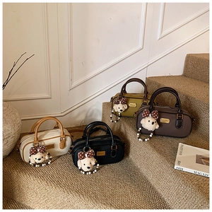 Detailed view of boston bags in four colors with plush bear charms on beige stairs
