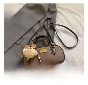 Close-up of brown pebbled leather texture with gold logo plate and cute bear charm detail