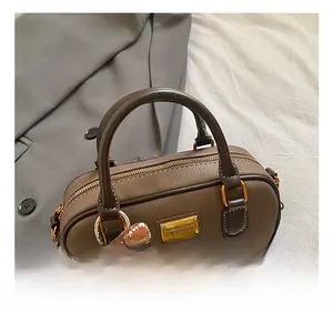 Detail of dark brown lychee leather handbag with golden hardware and plush dog charm