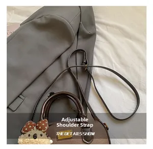 Detail of brown leather handbag featuring adjustable strap and plush bear charm decoration