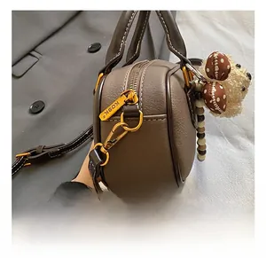 Close-up of brown lychee grain leather handbag with gold zipper and cute dog pendant