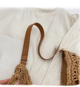 Close-up of brown leather handles and woven texture on a large beach tote bag