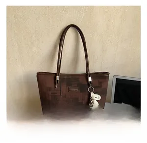 Detail of deep brown textured bucket bag with leather strap and horse charm