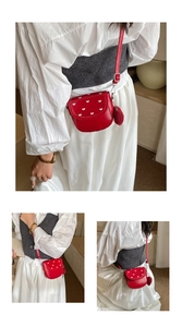 Detalle de mini bolso rojo con estampado de corazones, colgante de felpa y correa fina