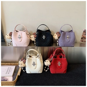 Detail view of five colored bucket bags with plush bear charms and metal turn-lock closure