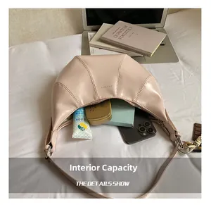 Internal capacity of the beige crescent shoulder bag showing phone and cosmetics