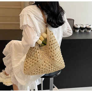 Detail of hollow out woven beach tote with brown leather strap and floral pattern