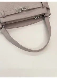 Detail of lavender litchi grain leather bag with silver metal lock and wide handle