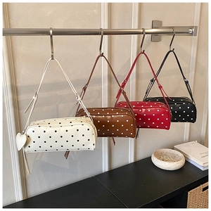 Detailed display of four color polka dot shoulder bags with heart charms on metal stands