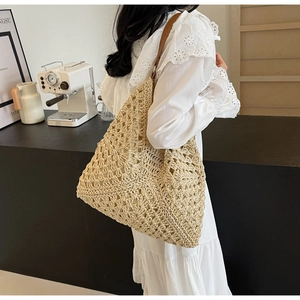 Detail of hollow woven beach tote featuring beige crochet patterns and brown leather strap