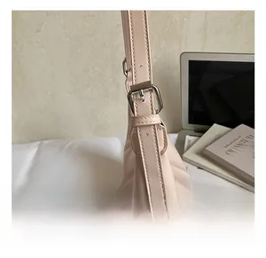 Detail of adjustable leather shoulder strap with silver metal buckle on a beige bag