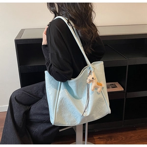 Detail of light blue wrinkled faux leather tote bag with a small brown horse charm