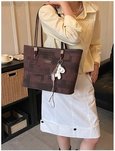 Detail view of brown large tote bag with horse charm on a model in home setting