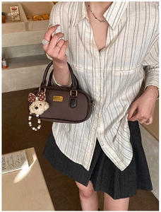 Detailed macro view of a brown mini Boston bag with plush bear charm and golden hardware