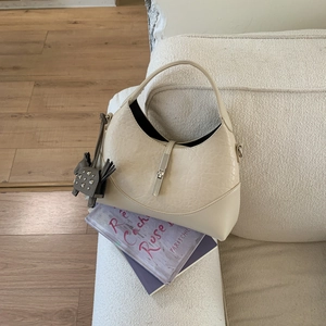 Close-up of beige moon bag with crocodile texture, silver clasp and elephant charm