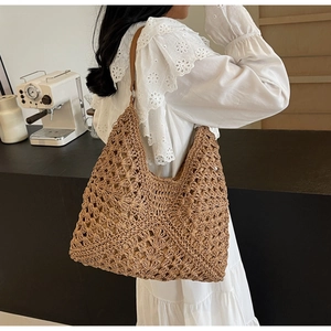 Detailed view of hollow woven straw tote bag with brown leather strap and intricate patterns