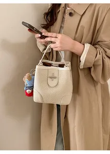 Detail view of cream bucket bag with embossed leather texture and cute bear charm