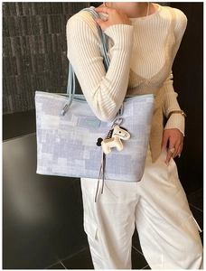 Detail of pixel-textured tote bag with light blue leather strap and pony charm